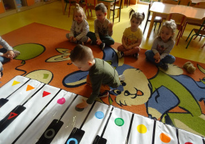 Chłopiec odszukuje wylosowaną figurę geometryczną na jednym z klawiszy instrumentu Kolorpiano.